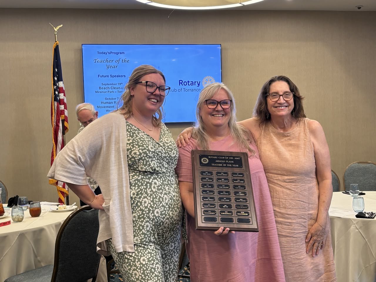 Susan Eriksen holding the Arnold Plank Teacher of the Year plaque with two guests