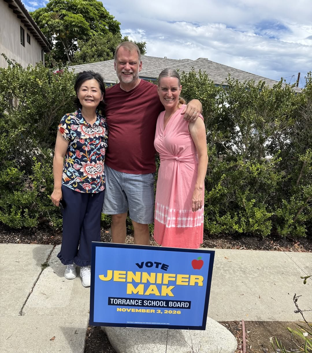 Jennifer Mak standing with a couple beside a Vote Jennifer Mak yard sign