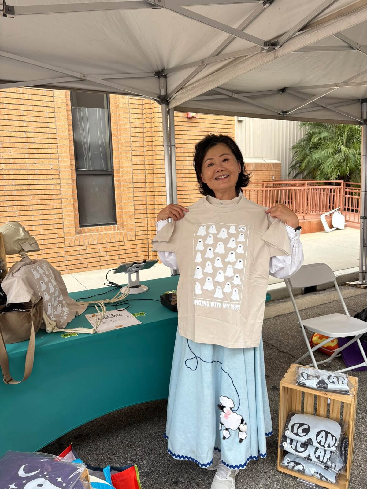 Jennifer Mak holding up a ghost-print T-shirt at the ICAN table