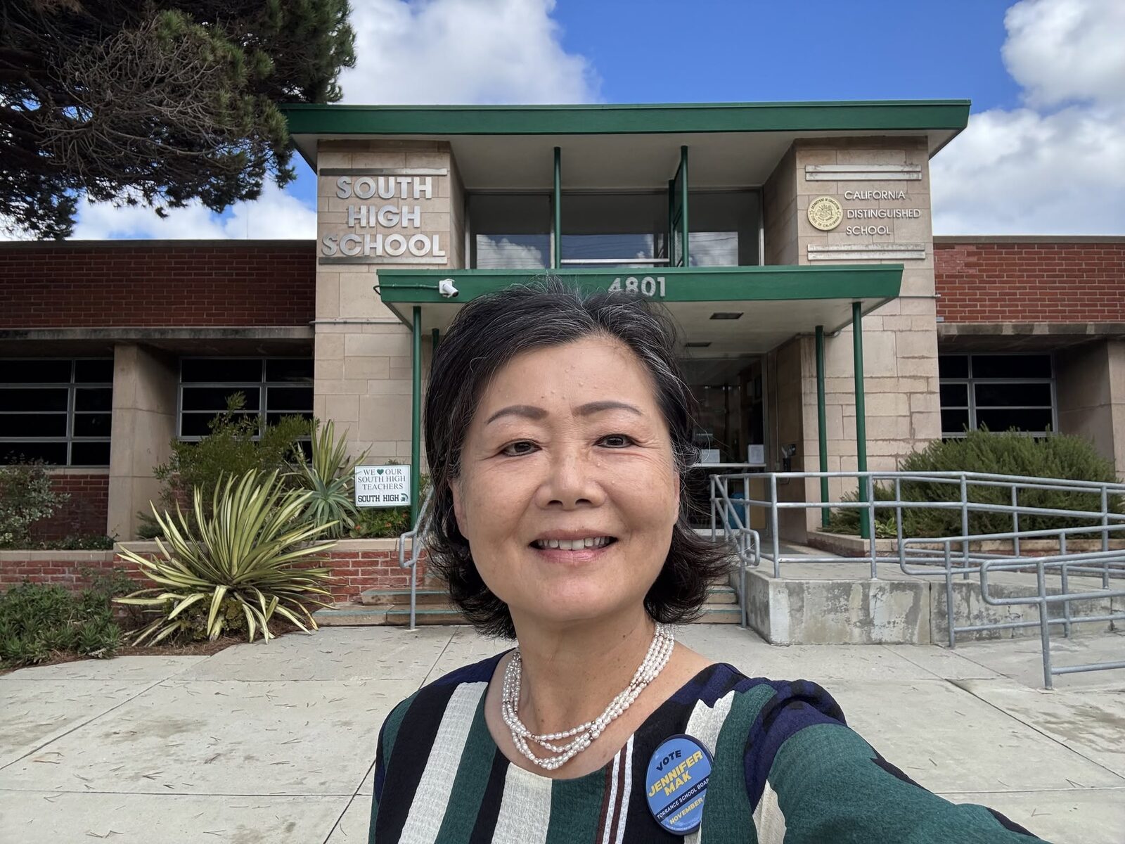 Jennifer Mak in front of the South High School entrance, wearing her campaign button